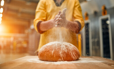 The baker sprinkles flour on the freshly baked bread. Automated bread production.