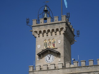 San Marino, Public Palace. Closeup on the crenellated clock tower with the mosaic and the coats of arms of the four Castles of the Republic