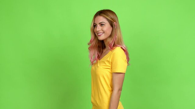 Young blonde woman posing with arms at hip and laughing over isolated background on green screen chroma key