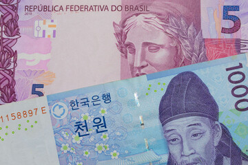 A macro image of a blue and white one thousand won bill from Korea paired up with a pink and purple five real bank note from Brazil.  Shot close up in macro.