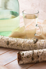 Birch sap juice in a glass mug with a birch stump