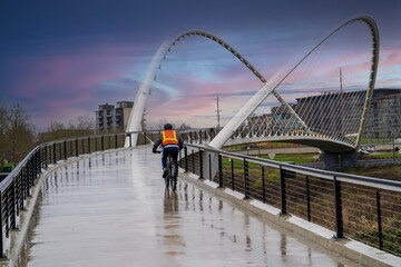 A man on a bicycle riding across the Peter Courtney Minto Island pedestrian bridge in Salem, Oregon