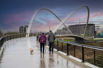 A man and woman walking with dog across the Peter Courtney Minto Island pedestrian bridge in Salem,...