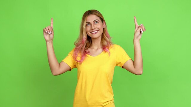 Young blonde woman pointing a great idea and looking up over isolated background on green screen chroma key