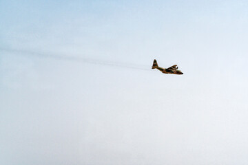 a camouflaged military air cargo transport plane in flight over the negev desert in a clear blue...