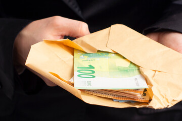 a woman in a black suit holds an envelope with euro banknotes. Business concept © Alena