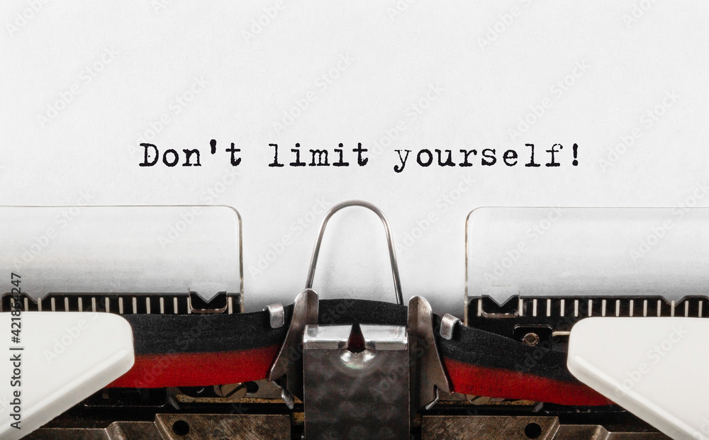 Poster text don't limit yourself typed on retro typewriter