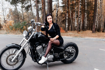 Obraz na płótnie Canvas beautiful brunette in a dress on a motorcycle in the park