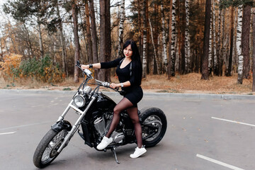 Fototapeta na wymiar beautiful brunette in a dress on a motorcycle in the park
