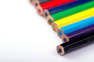 Various colored wooden pencil crayons placed in a row in front of a white isolated background