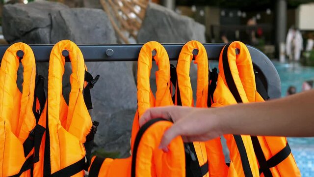 Orange life jackets. Life jackets are neatly hung out in front of the open water pool and are ready to use. Safety on the water.