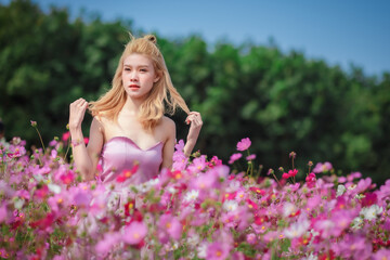 Obraz na płótnie Canvas Beautiful girl in a field of cosmos flowers on a sunny day