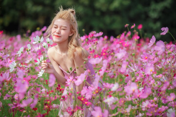Beautiful girl in a field of cosmos flowers  on a sunny day