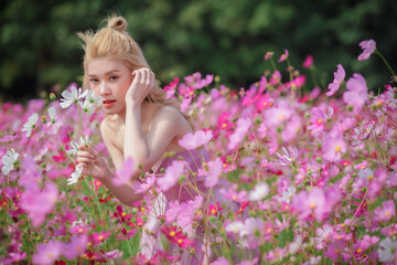 Beautiful girl in a field of cosmos flowers on a sunny day