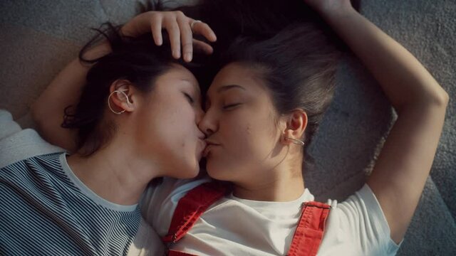 Happy Lesbian Couple at Home Lying,  Kissing, Cuddle, Touch Tenderly. Sunny Day Two Sensuous Girlfriends in Love Spend time Together, Share Authentic Beautiful Moments. Top Down Above Close-up Shot