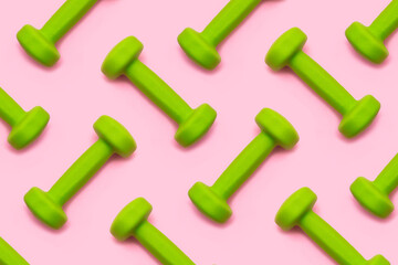 Lots of green dumbbells isolated on pink background. Pattern. Healthy lifestyle. Sport equipment....