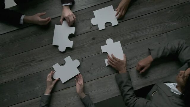 Business teamwork with white puzzle of four pieces cooperation unity concept