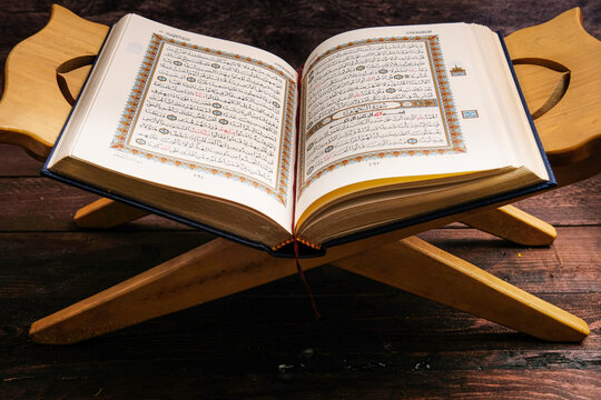 An Open Page Of Quran Shows Surah Al Kahf On Brown Background. 