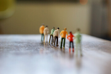 Miniature figurine character queuing on the one line by social distancing, selected focus, Covid 19 concept