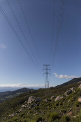 power lines in the middle of the field, in a mountain area, the sky is blue and there is abundant green vegetation