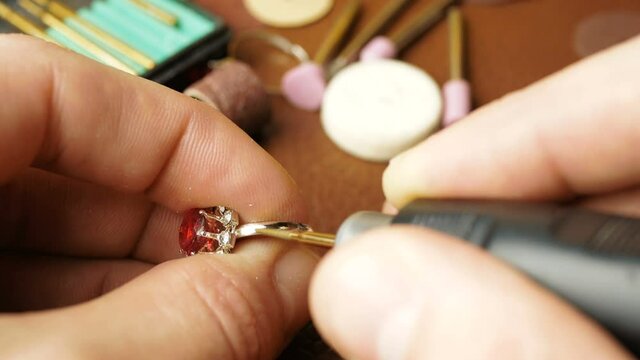 A professional engraver creates a piece of jewelry. Jewelry processing, gemstone polishing by a professional jeweler.A jeweler is cutting a precious stone on a gold ring. A professional jeweler