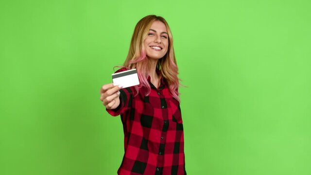 Young blonde woman happy and holding a credit card over isolated background on green screen chroma key