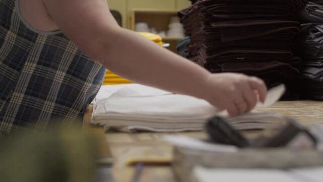 An employee of a garment factory lays out manufactured products, working day at the clothing factory, fabric production