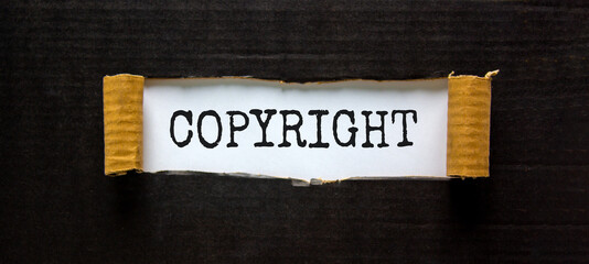 Copyright symbol. The word 'Copyright' appearing behind torn black paper. Beautiful black background. Business, copyright concept. Copy space.
