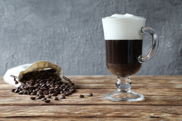 A glass of Irish coffee with coffee beans in a bag