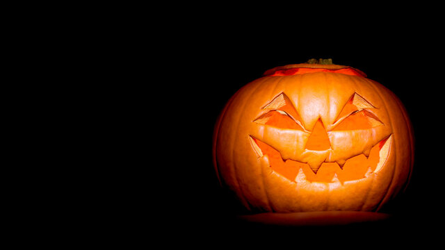 Halloween jack-o-lantern (will-o-the-wisp) made from a pumpkin on black background with copy space for use as a header or banner
