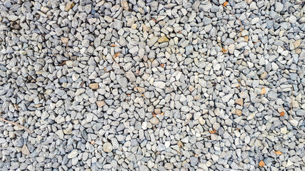 Gravel texture. Pebble stone background. Light grey closeup small rocks. Top