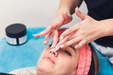 the beautician applies a moisturizer to the skin of the face