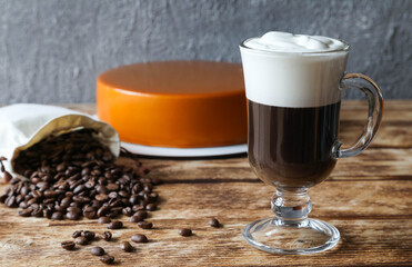 Irish coffee with cake in the background and coffee beans in a bag
