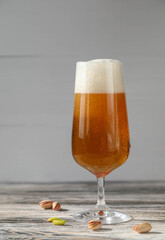 A glass of beer with foam with pistachios