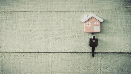 House model and key hanging on the wall. Real estate agent offer house, property insurance and security, affordable housing concepts