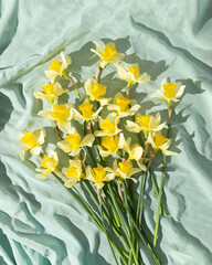Yellow narcissus flowers bouquet on bright green fabric. Minimal spring arrangement. Flat lay.