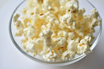 Glass saucer with popcorn on a white background