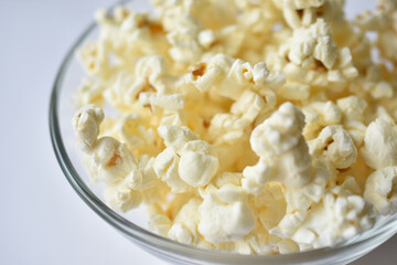 Glass saucer with popcorn on a white background