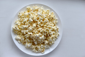 Delicious popcorn on a white plate close-up