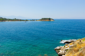 Horizontal view of the turquoise waters of the sea. Wild clifs in front of turquoise water. Summer vacation by the sea