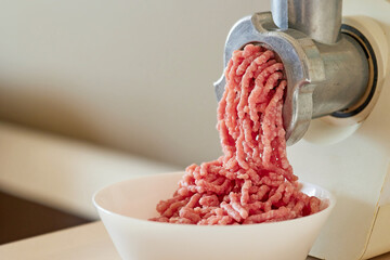 mince the meat with an electric meat mincer - obrazy, fototapety, plakaty