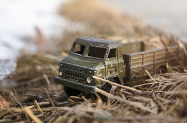 Toy military vehicle on dry grass outdoors