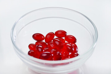 Krill oil capsules. Red gelatin capsules with krill oil in a glass  cup on a white background.Source of omega fatty acids.Dietary supplement .Healthy food.krill oil supplements