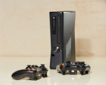 Minsk, Belarus - FEBRUARY 03, 2021: Front view of the used XBOX 360 Slim (Corona) 250GB Console and two gamepads on the table.