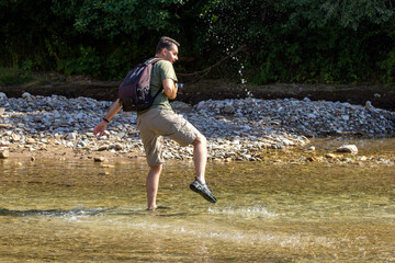 A young man dancing on the water on a sunny day, on a mountain river. © NAIL BATTALOV