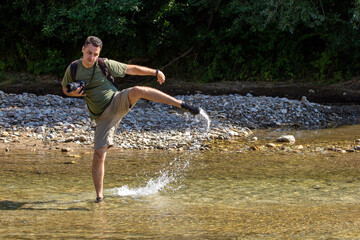 A young man dancing on the water on a sunny day, on a mountain river. © NAIL BATTALOV