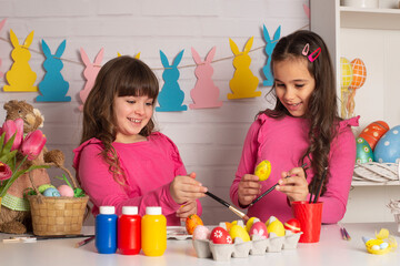 Happy Easter! Two cute little creative girls are painting eggs  hare getting ready for holiday
