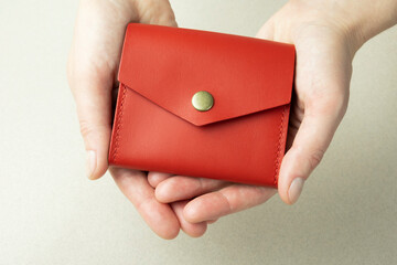 red leather wallet in open female hands close-up on gray background with shadows
