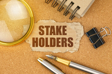 On the table are office items and a cardboard with the inscription - STAKE HOLDERS