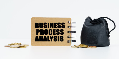 On a white background lies a bag with money, coins and a notebook with the inscription - BUSINESS PROCESS ANALYSIS